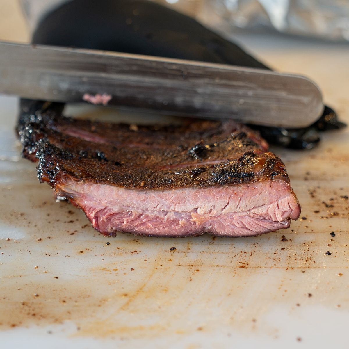 Slicing into a peppered prime brisket on the cutting board
