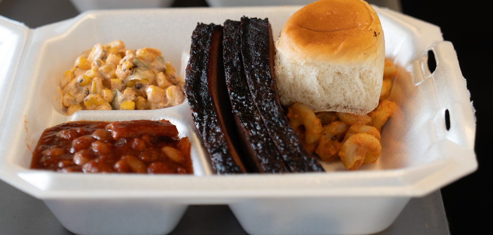 BBQ plate packed to go — St. Louis ribs, mac & cheese, baked beans, street corn and a roll
